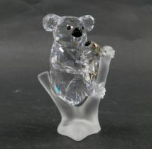 A Swarovski crystal figure group of two koala bears, mother and baby, perched on branch, with black