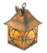 An Arts and Crafts style hammered and patinated copper lantern, with amber tinted glass, 33cm high.