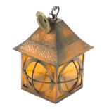 An Arts and Crafts style hammered and patinated copper lantern, with amber tinted glass, 33cm high.