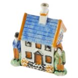 A 19thC Prattware money box, modelled as a cottage, with two figures, 15cm high, 11cm wide, 7cm deep