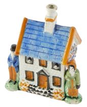 A 19thC Prattware money box, modelled as a cottage, with two figures, 15cm high, 11cm wide, 7cm deep