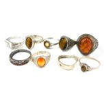 A group of white metal dress rings, to include some stone set with imitation amber, tigers eye, and