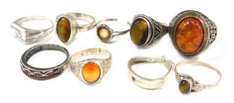 A group of white metal dress rings, to include some stone set with imitation amber, tigers eye, and