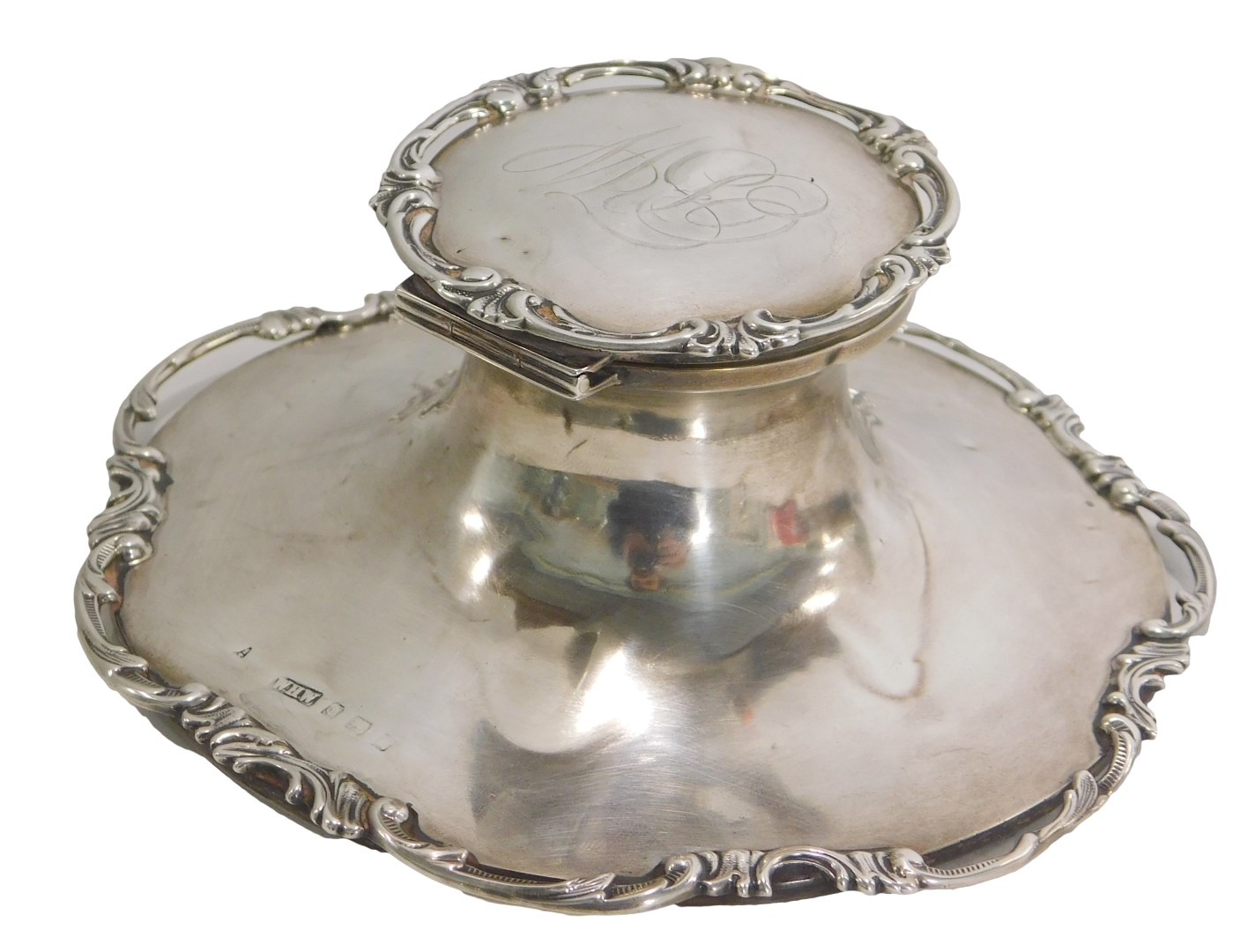 A George V silver inkwell, with c-scroll rococo border to top and base rim, bearing the initials BW,