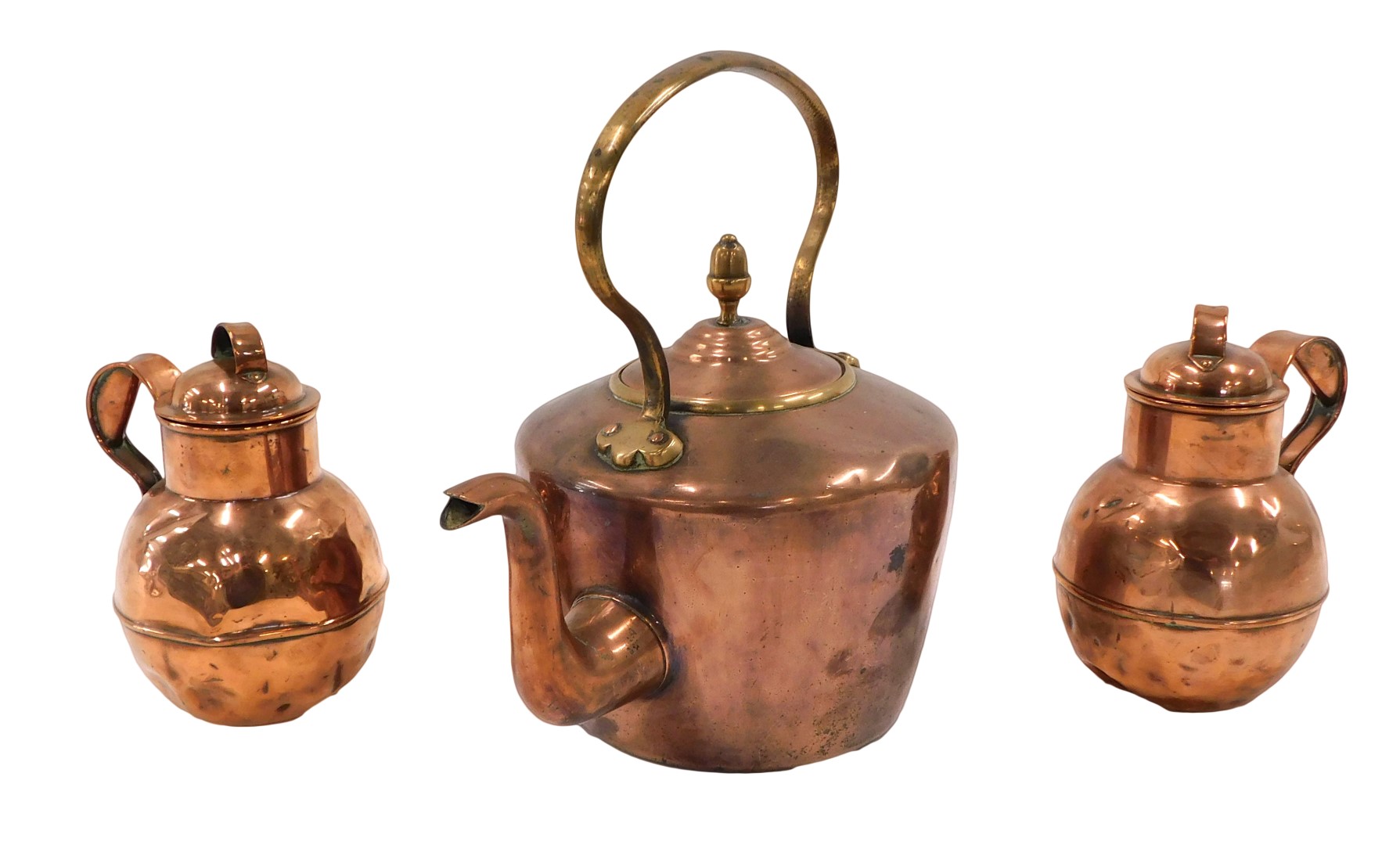 A Victorian copper kettle, and two copper Army and Navy Jersey type cream jugs.