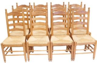 A set of twelve oak ladder back dining chairs, each with a rush seat, on turned legs with stretchers