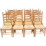 A set of twelve oak ladder back dining chairs, each with a rush seat, on turned legs with stretchers