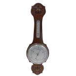 An Edwardian mahogany aneroid wheel shaped barometer with thermometer, in a carved case, 82cm high.