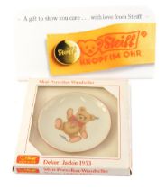 A Steiff small collectors plate Jackie 1953, and a white Perspex Steiff advertising plaque.