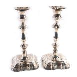 A pair of Elizabeth II silver candlesticks, of fluted form, on a stepped base loaded with green baiz