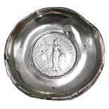 A white metal pin dish, the hammered coin centre bearing a 1911 one dollar, in a white metal border,