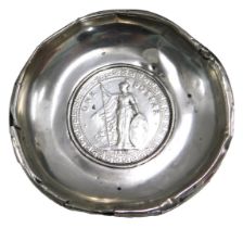 A white metal pin dish, the hammered coin centre bearing a 1911 one dollar, in a white metal border,