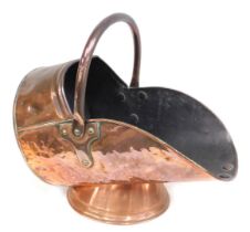 A late 19th/early 20thC copper helmet shaped coal scuttle, with swing handle and domed foot.