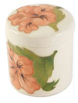 A Moorcroft lidded pot, cylindrical form, on a cream ground, with pink flowers, 9cm high.