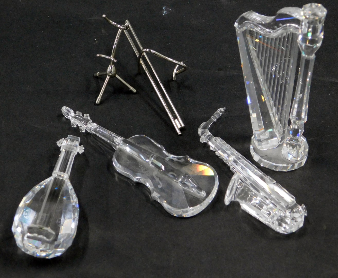 Four Swarovski crystal musical instruments, comprising harp, saxophone, cello and violin, some with