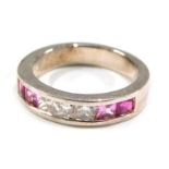 A dress ring, set with pink and white square set stones, channel set, on a white metal setting stamp