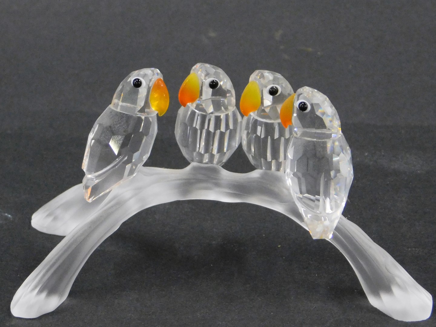 A Swarovski crystal figure group, of four parakeets on perch, each with an orange and yellow crystal