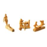 Three carved wooden animal figure groups, comprising goats on saw, man fishing, and bear playing p