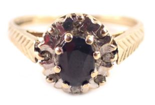 A 9ct gold cluster ring, with oval sapphire, surrounded by tiny diamond and illusion border, with ch