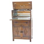 An Old Charm style oak cocktail cabinet, the double hinged top enclosing a mirrored interior, carved