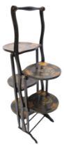 An early 20thC black Japanned double sided four tier folding cake stand, decorated with buildings, f