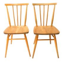 A pair of light coloured Ercol stick back kitchen chairs, each with an elm seat with turned back and