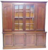 A continental walnut bookcase, the top with a moulded cornice above two glazed doors, flanked by two