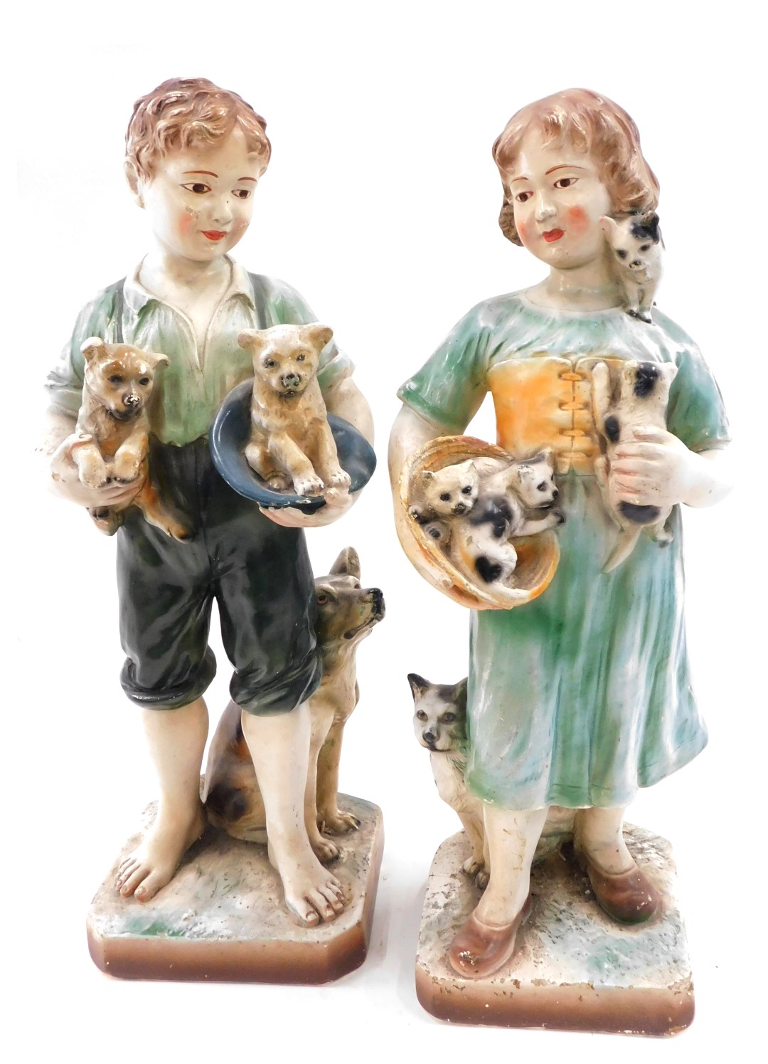 A pair of early 20thC painted chalkware figures, of a girl with kittens and a boy with puppies, 50cm