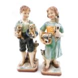 A pair of early 20thC painted chalkware figures, of a girl with kittens and a boy with puppies, 50cm