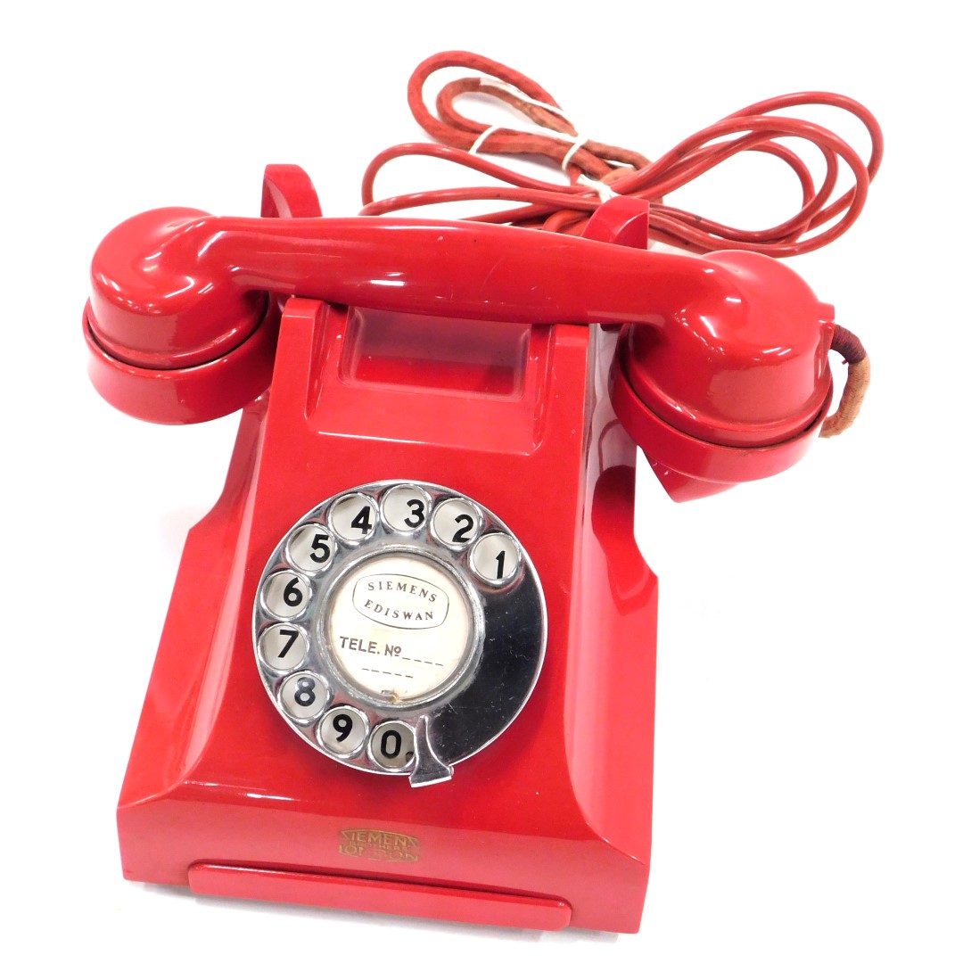 A red coloured telephone, stamped in gilt Siemens Brothers London.