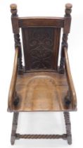 A carved oak child's highchair in 18thC style, with a carved back, shaped arms and solid seat, on sp