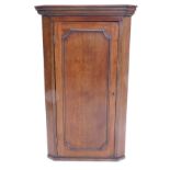 An early 19thC oak hanging corner cupboard, with single panelled door, 115cm high, 68cm wide.