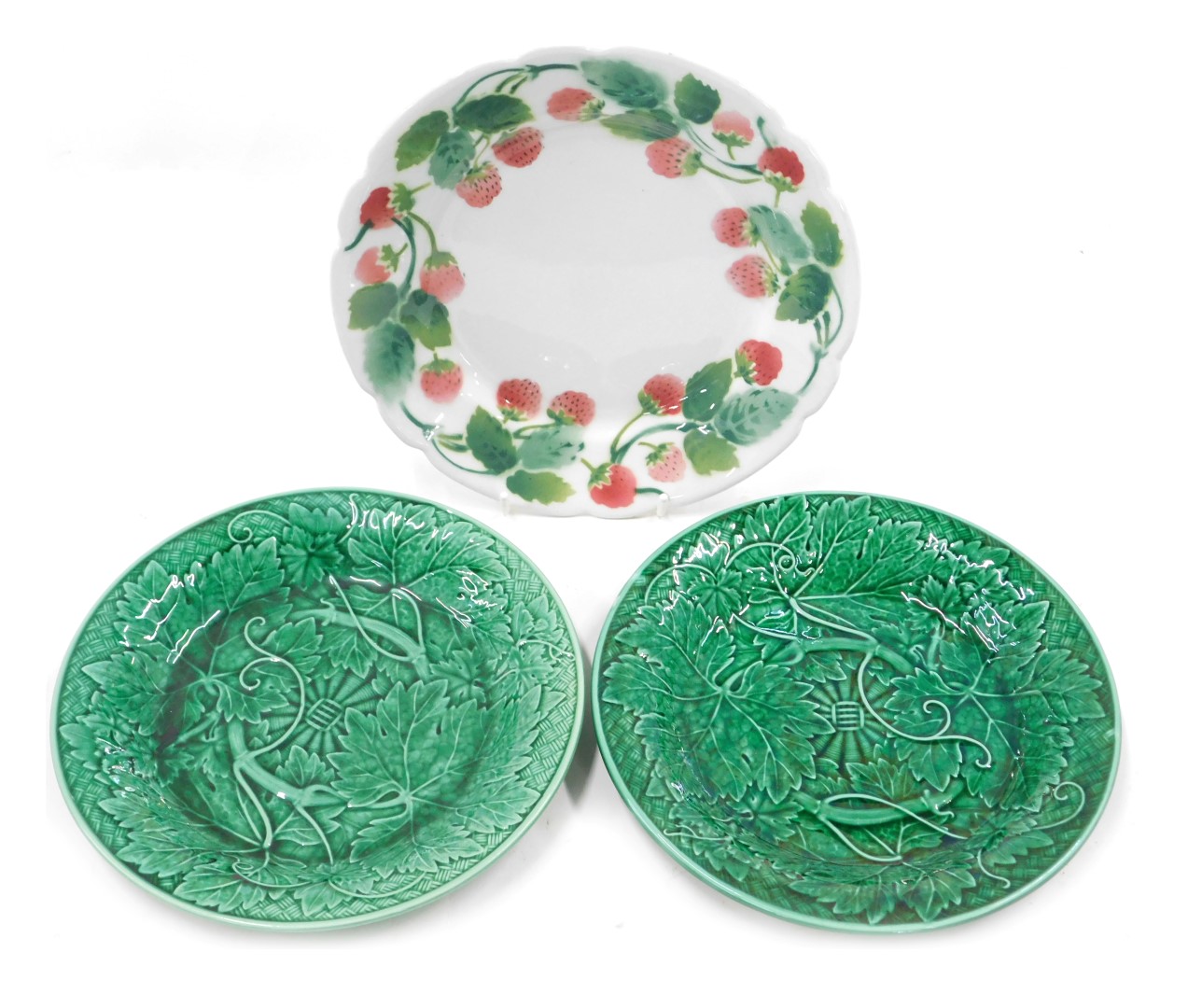 A French Luneville plate decorated with a band of strawberries, and two Wedgwood green leaf moulded