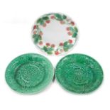 A French Luneville plate decorated with a band of strawberries, and two Wedgwood green leaf moulded