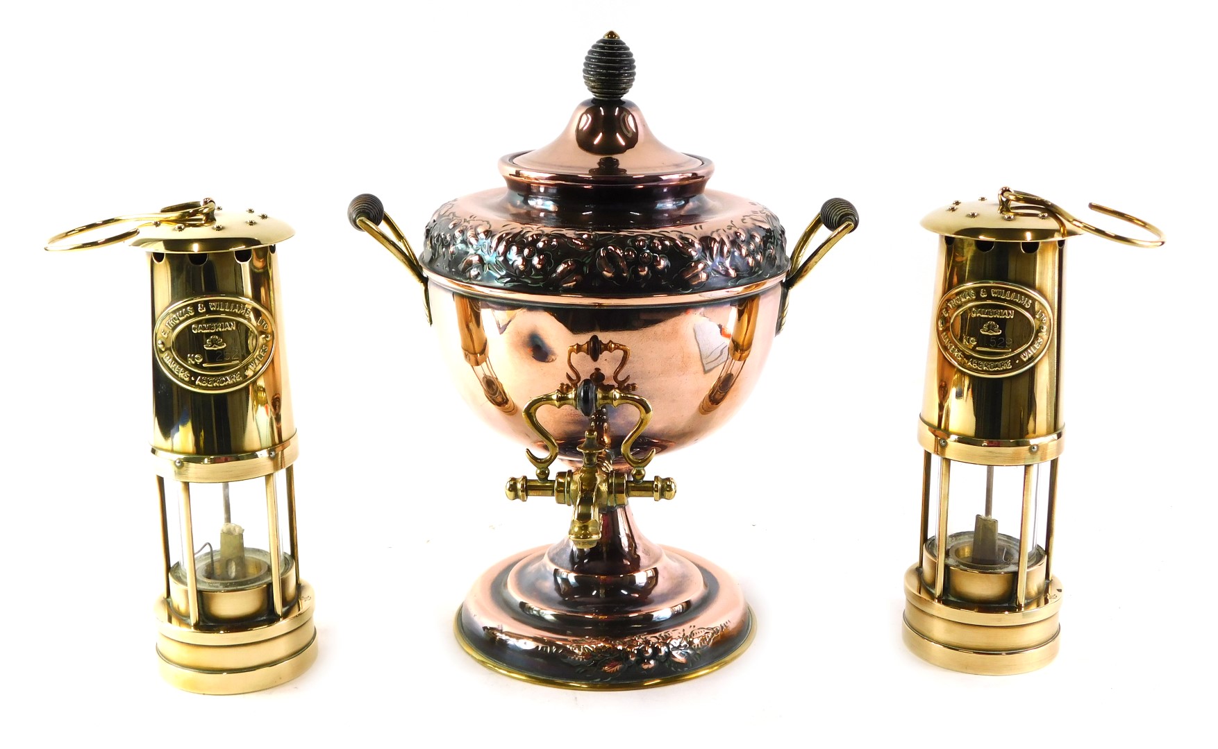 A brass and embossed copper two handled tea urn, 36cm high, and two Thomas and Williams miner's lamp