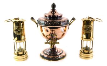 A brass and embossed copper two handled tea urn, 36cm high, and two Thomas and Williams miner's lamp