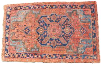 A Persian rug, with a design of geometric motifs, on a red ground with part pale blue spandrels, one