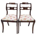 A pair of Regency dining chairs, each with a carved back, drop in seat, on sabre legs.