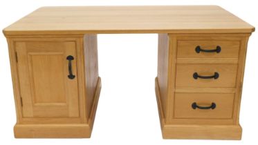 A light oak partner's kneehole desk, rectangular top with canted corners above an arrangement of fal