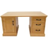 A light oak partner's kneehole desk, rectangular top with canted corners above an arrangement of fal