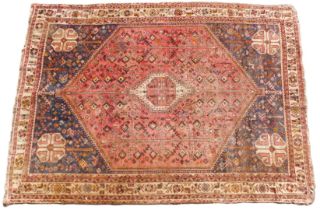 A Persian rug, with an all over geometric design, on a red ground with blue spandrels, one wide and