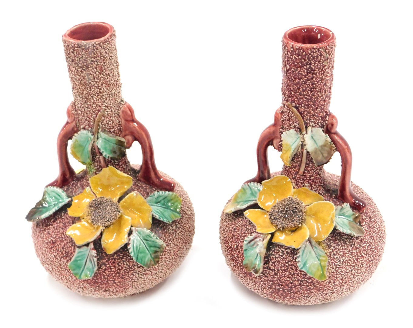 A pair of Continental Majolica two handled vases, each with flower encrusted decoration, on a red gr
