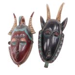 An African tribal mask, with two horns, with a black face, etc., 50cm high, and a similar mask with