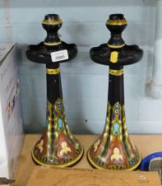 A pair of Thaller Gouda candle stands, each on a black floral ground, marked Holland to underside, 3