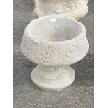 A reconstituted stone fleur de lys pattern urn, stylised with three petal design, on a circular foot