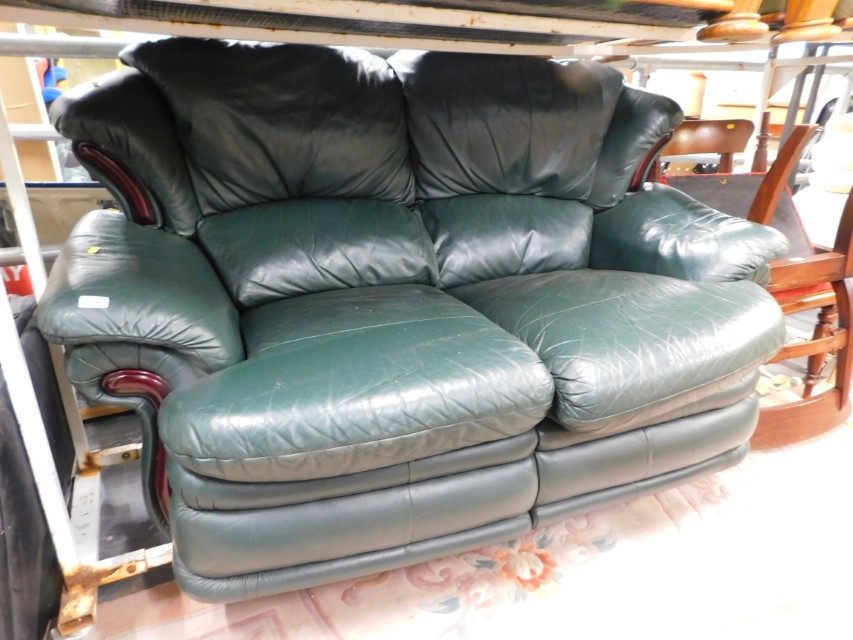 A green leatherette two seater sofa.