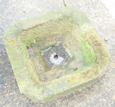 A hard hewn stone square planter.