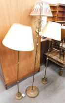 Three brass standard lamps, comprising one with arched top and cream and red shade, 150cm high, each