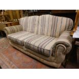 A cream upholstered two seater sofa in cream floral striped fabric.