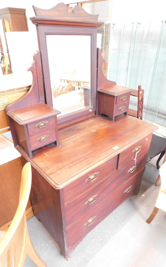 An Edwardian walnut dressing chest, with arch mirror back above two draw pillars, the base with two